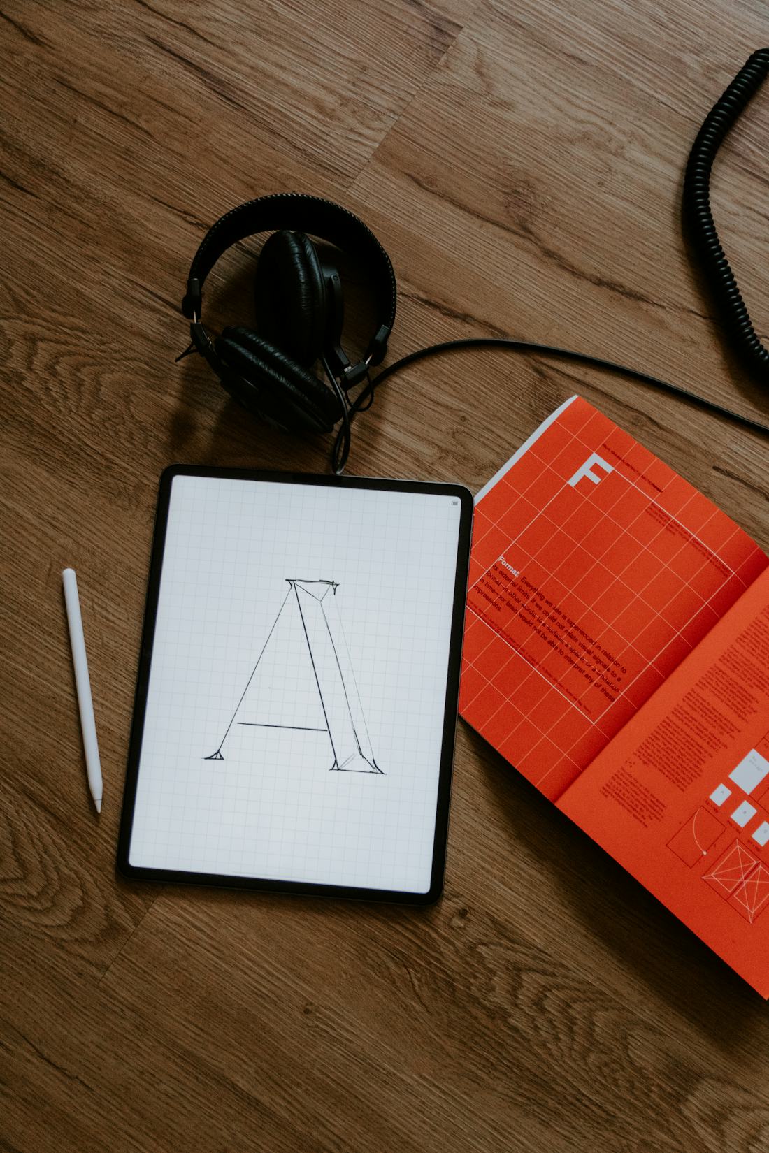 Content globalization — typeface design proofs on a tablet beside an orange print typography manual